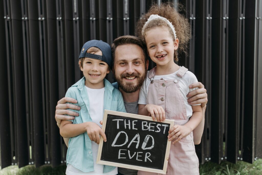 A joyful father hugging his children with a "Best Dad Ever" sign.